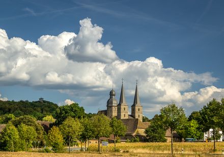 Abtei Marienmünster mit zwei markanten Kirchspitzen in malerischer Landschaft vor blauem Himmel.