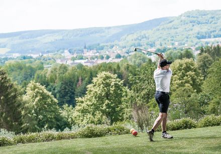 Mann spielt Golf auf dem Golfplatz mit Aussicht auf Bad Driburg. 