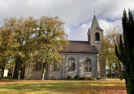 Alte Dorfkirche in Augustdorf, von Bäumen umgeben, hervorgehoben durch ziegelgedecktes Dach und Turm.