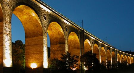Das Altenbekener Viadukt erstrahlt nachts in warmem Licht, seine Bögen heben sich eindrucksvoll ab.
