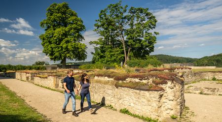 Zwei Personen spazieren an den Ruinen der historischen Stadtmauer von Bielefeld entlang.