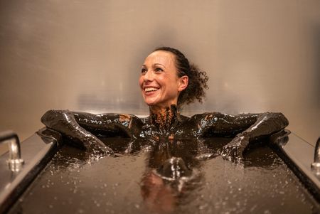 Frau liegt in Moorwanne und schaut lächelnd zur Seite