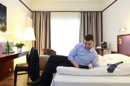Zimmer mit Mann auf einem Bett im Hotel Mercure City Bad Oeynhausen