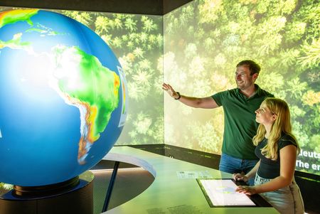 Mann und ein Kind schauen sich Weltkugel in der Klimaerlebniswelt Oerlinghausen an