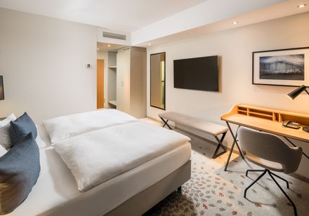 Modern gestaltetes Hotelzimmer mit Doppelbett und Schreibtisch