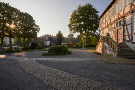 Historisches Fachwerkhaus in Borchen, umgeben von gepflegten Gärten bei Sonnenaufgang.