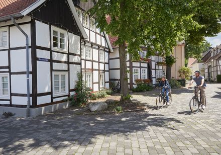 Zwei Personen fahren mit Fahrrädern durch Rietberg mit historischen Fachwerkhäusern.