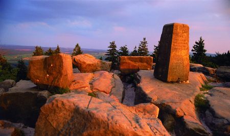 Felsige Landschaft bei Sonnenuntergang auf dem Lippischen Velmerstot mit Inschriftstein im Vordergrund.