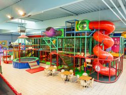 Ein bunter Indoor-Spielplatz mit Kletterstrukturen, Rutschen und Trampolin bietet vielseitigen Spielspaß.