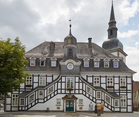 Historisches Fachwerk-Rathaus in Rietberg mit markantem Turm in schiefergrauen Tönen, umgeben von Pflastersteinen.