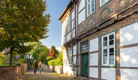 Fachwerkhaus in Blomberg mit dekorierten Balken, gepflasterte Straße und Spaziergänger im Herbstlicht.