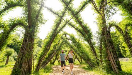 Paar geht durch die grünen Bögen des Weidenpalais Rheder