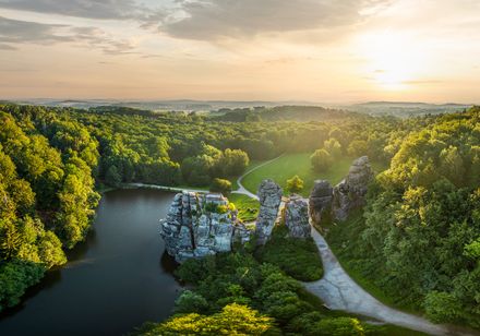 Luftaufnahme der Externsteine im Teutoburger Wald bei Sonnenuntergang, umgeben von dichten Wäldern.