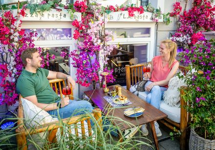 Zwei Personen genießen Getränke auf einer blumenbeschmückten Terrasse