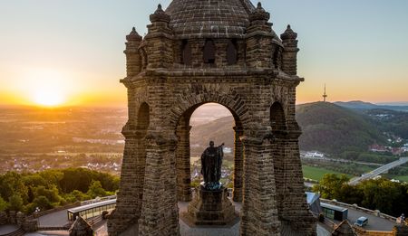 Das Bild zeigt das Kaiser-Wilhelm-Denkmal auf dem Wittekindsberg im Sonnenuntergang, Blick auf Landschaft.