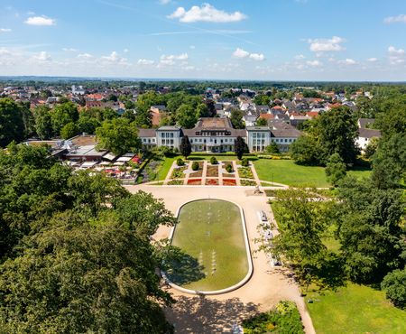 <p>Luftaufnahme von einem prachtvollen Schloss umgeben von einem weitläufigen, gepflegten Garten.</p>