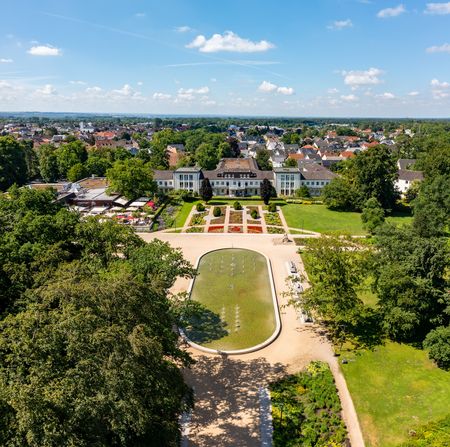 <p>Luftaufnahme von einem prachtvollen Schloss umgeben von einem weitläufigen, gepflegten Garten.</p>