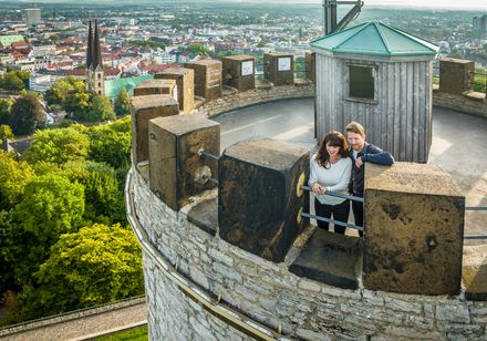 Pärchen auf dem Turm der Burg Gusen, mit Blick über die Stadt und grüne Landschaft im Hintergrund.