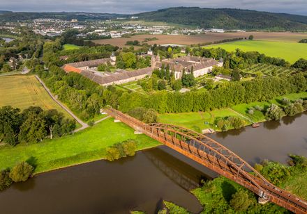 Luftaufnahme der Corvey-Eisenbahnbrücke über die Weser mit dem Schloss Corvey bei Höxter im Hintergrund.