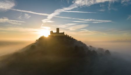 Desenberg im Morgenlicht, Sonnenstrahlen durchbrechen den Nebel, malerische Szene.