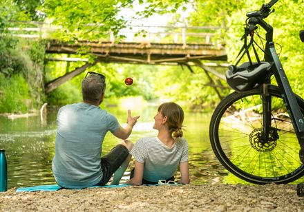 Paar macht Rast am Wasser, rechts Fahrräder
