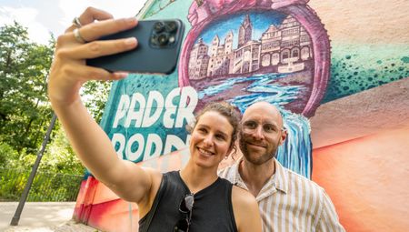 Zwei Personen machen ein Selfie vor dem Herzgraffiti in Paderborn