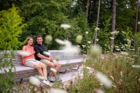 Paar sitzt auf Bank, vorne Blumen