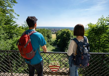 Zwei Wanderer mit Rucksäcken genießen von einem Aussichtspunkt aus den weiten Blick über die Landschaft.